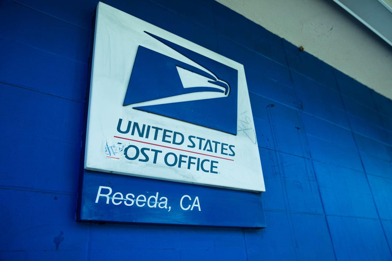 Close-up of the United States Post Office sign against a blue wall in Reseda, CA.